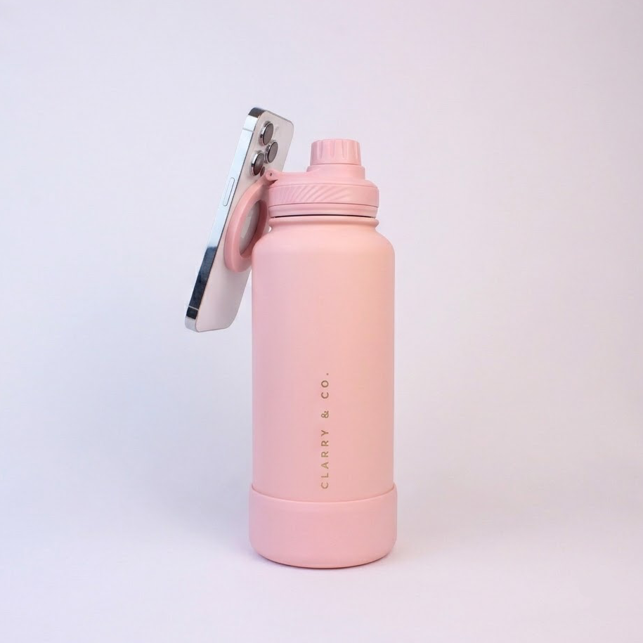 A light pink insulated water bottle with a matching pink cap and loop, featuring a silver smartphone attached to the side. The bottle has 'CLARY &amp; CO.
